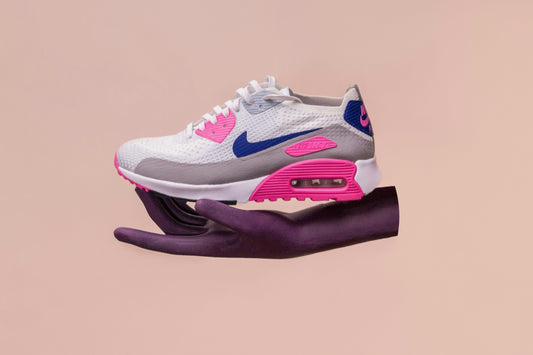 Stylish white, pink, and blue Nike Air Max sneaker displayed on a dark mannequin hand against a beige background.