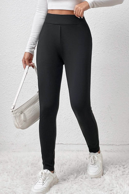 A person wearing cozy black high-waist sport leggings paired with a white top and sneakers, holding a white bag.