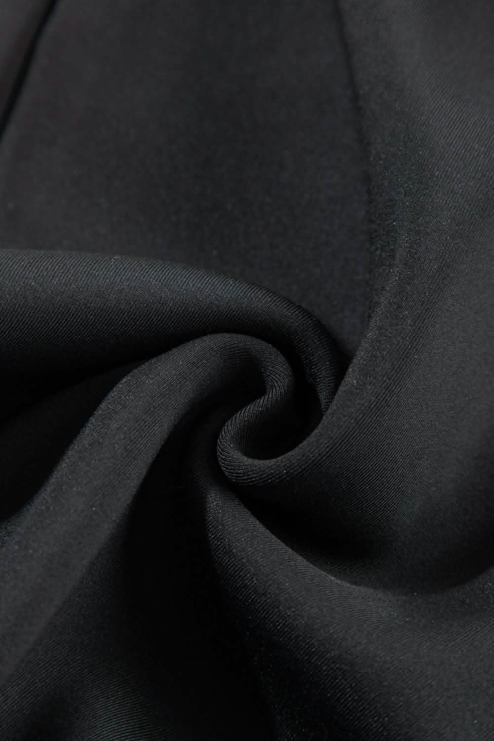 Swirled black fabric creating a spiral fold pattern.