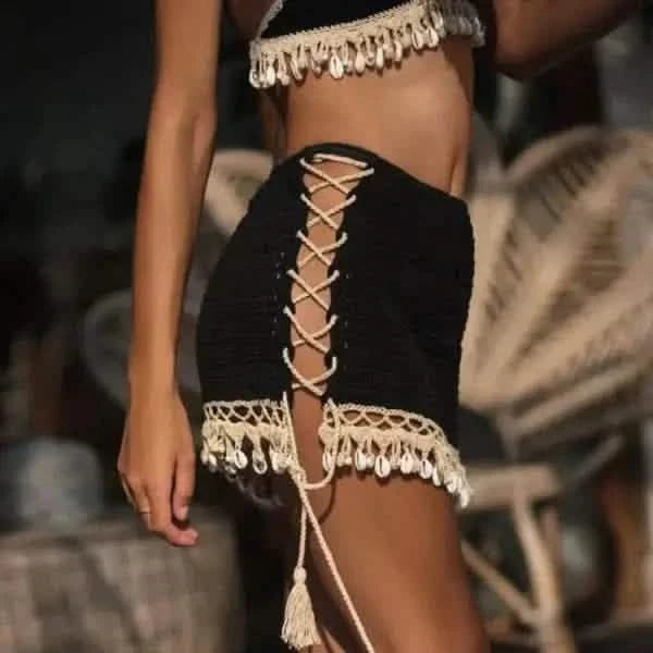 Black lace-up skirt with cream-colored tassel trim and fringe detailing.