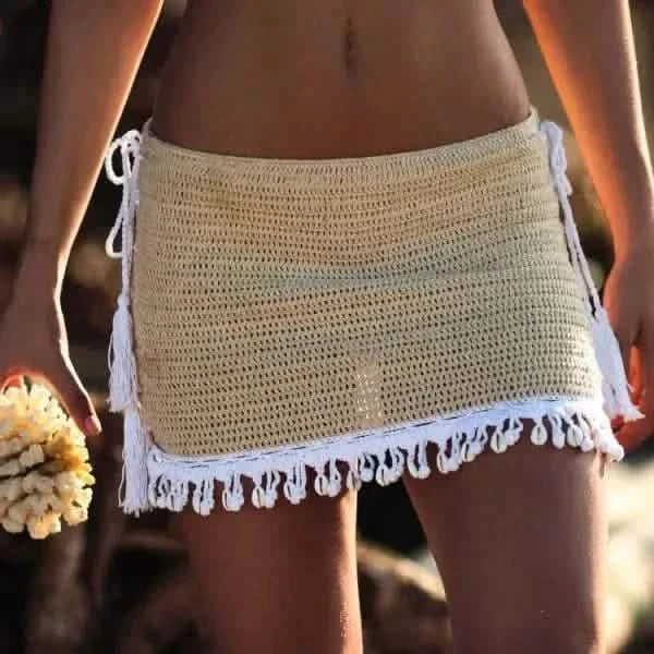 Crocheted beige beach skirt with white fringe trim along the bottom edge.