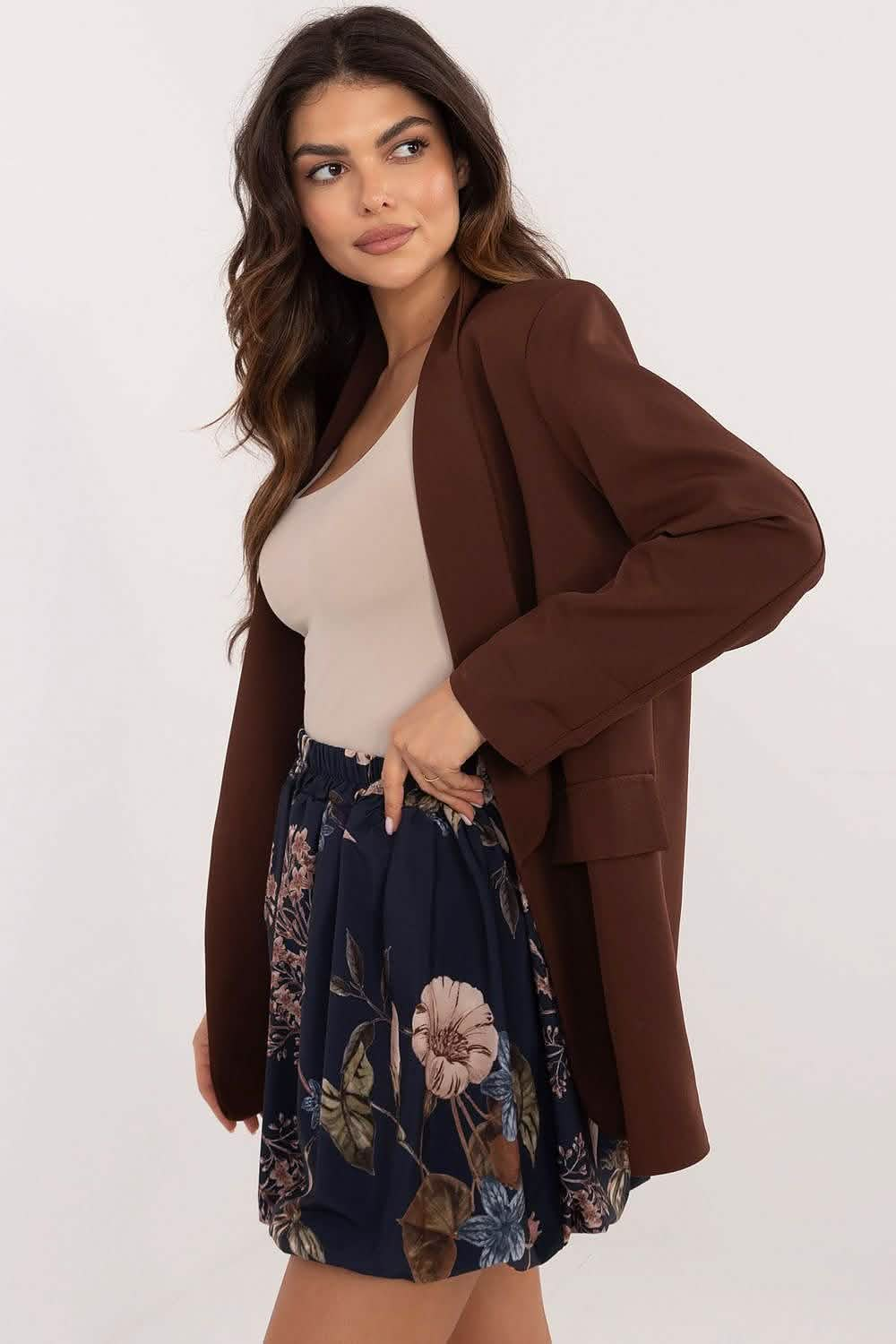 Long brown wool coat worn over a beige top and floral navy skirt.