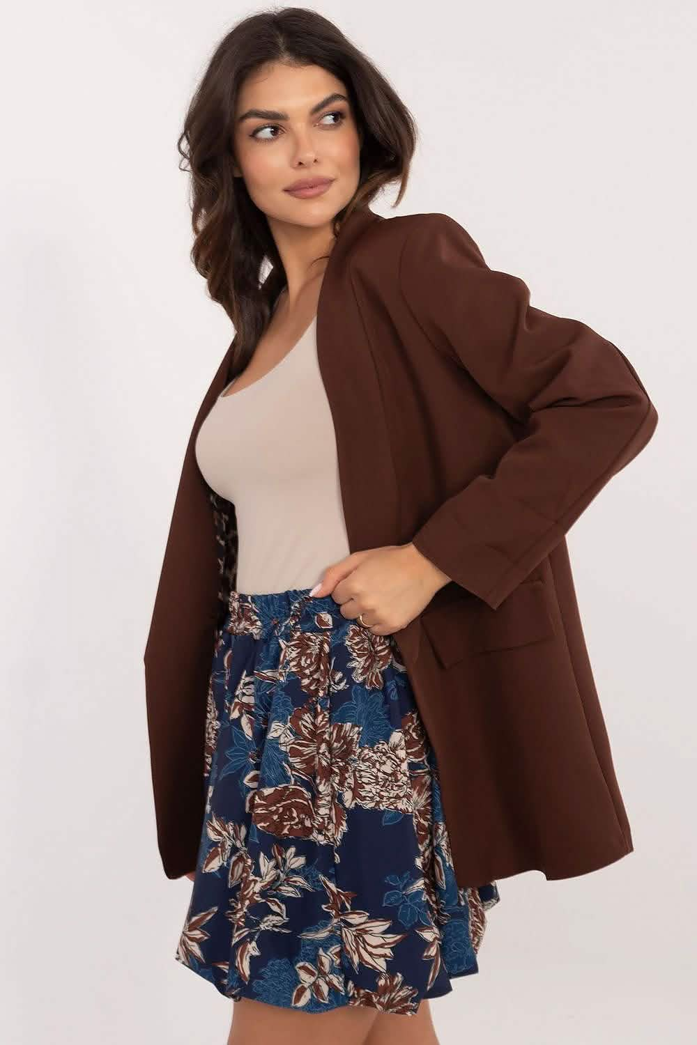 Brown oversized blazer worn with a beige top and floral navy skirt.