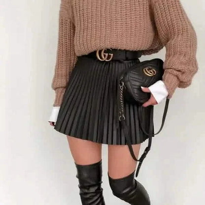 Stylish outfit featuring a beige sweater, black pleated skirt, Gucci belt, and knee-high boots.