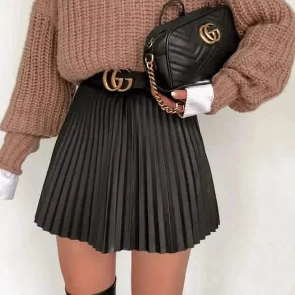 Black pleated mini skirt paired with a brown knit sweater and Gucci accessories.