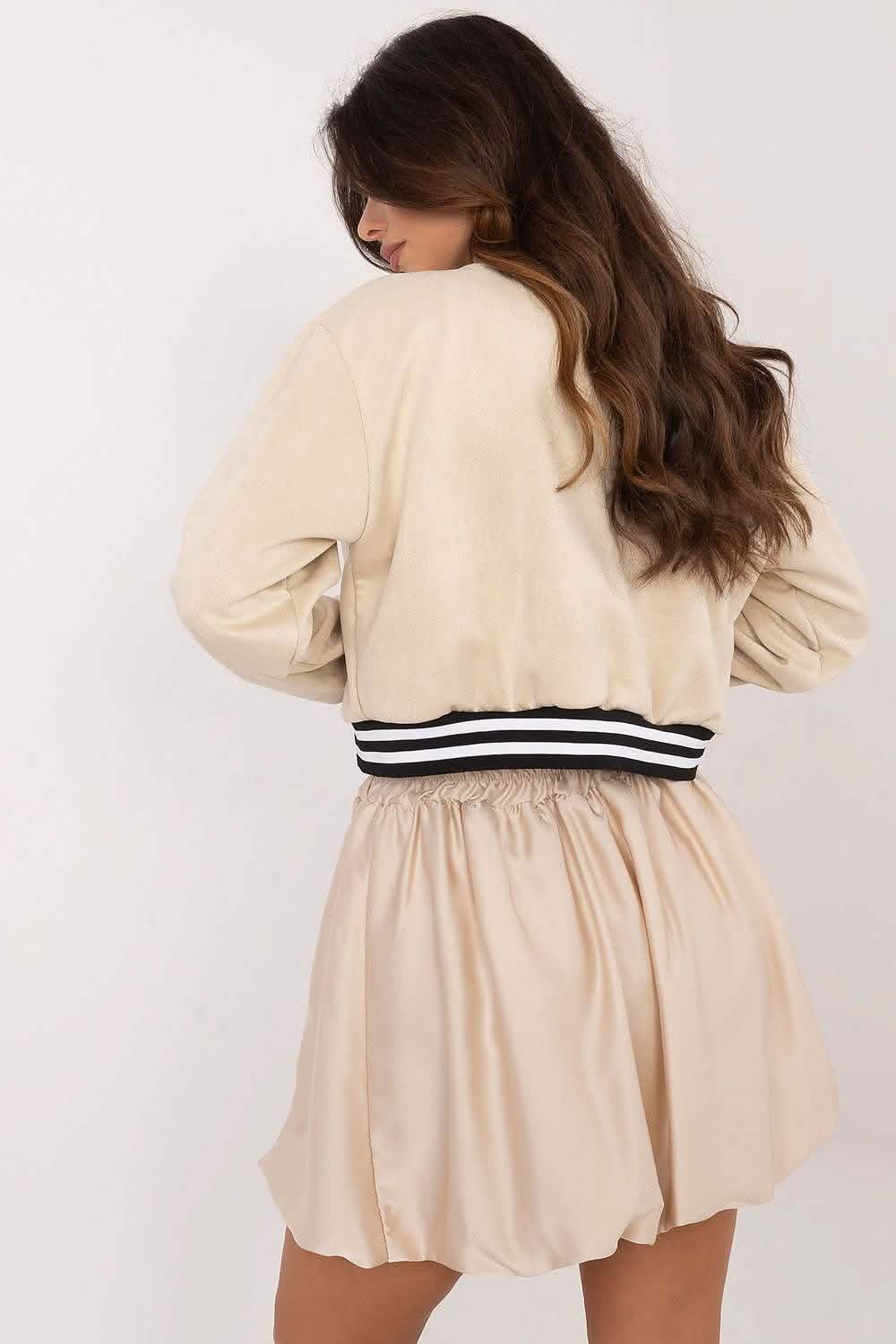 Cream-colored varsity jacket paired with a flowy beige skirt.