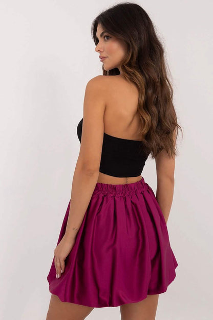 Magenta pleated mini skirt with gathered waist paired with a black crop top.