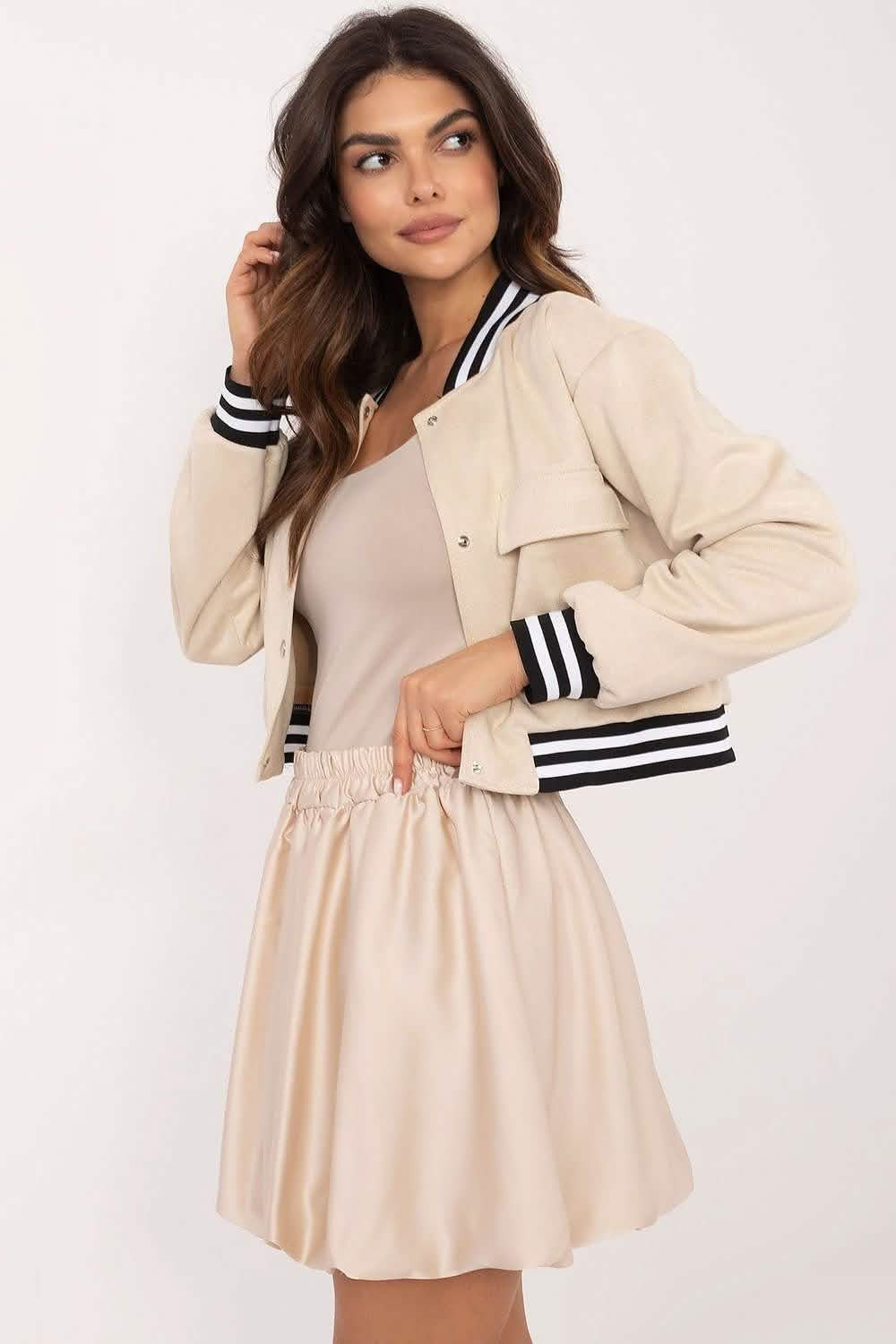 Beige varsity-style jacket with black and white striped ribbing worn over a light pink dress.