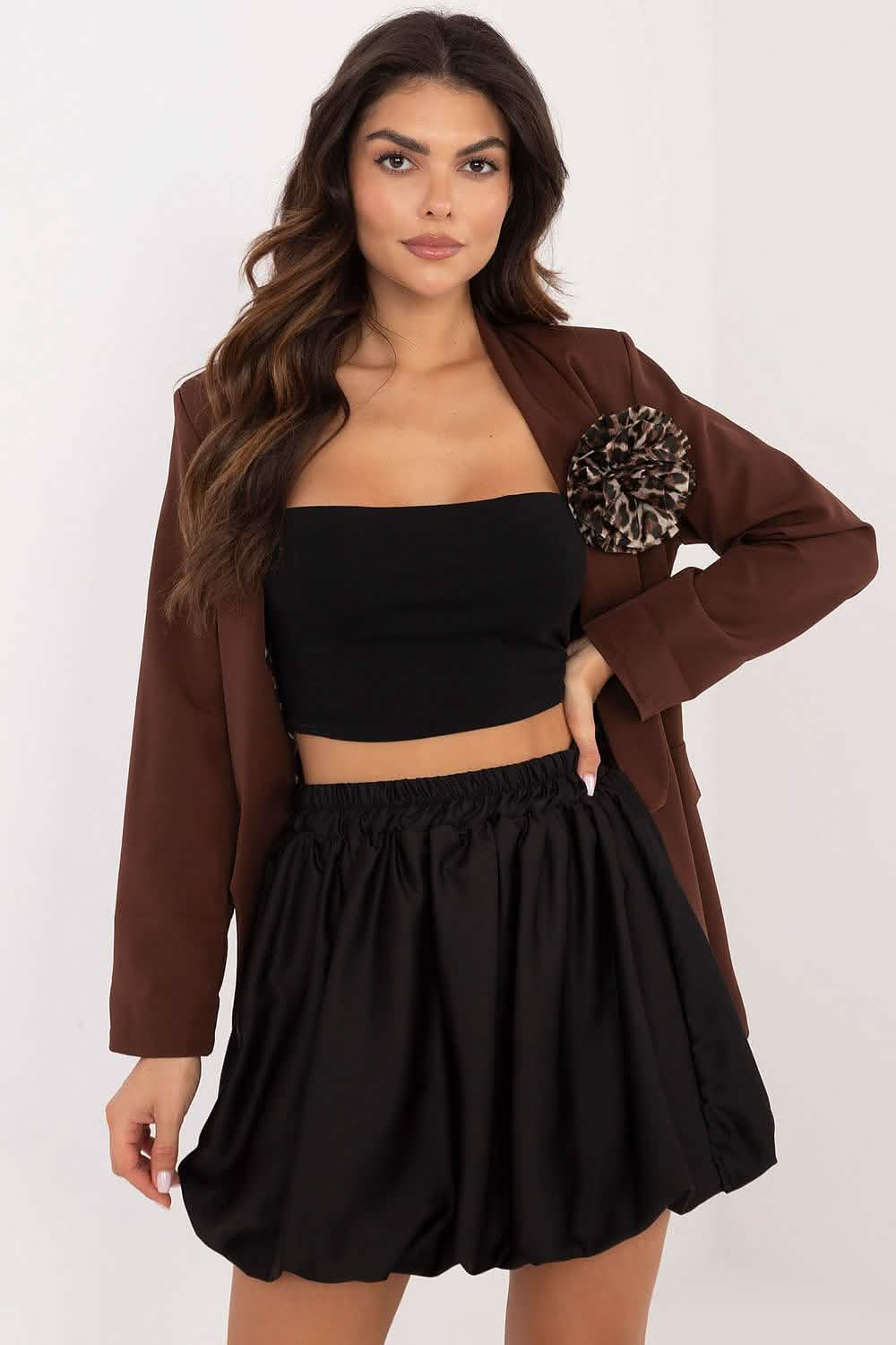 A brown blazer worn over a black crop top and bubble skirt outfit.