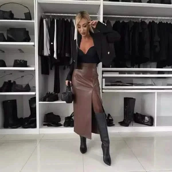 A stylish outfit featuring a black cropped top, brown leather midi skirt, and knee-high black boots.