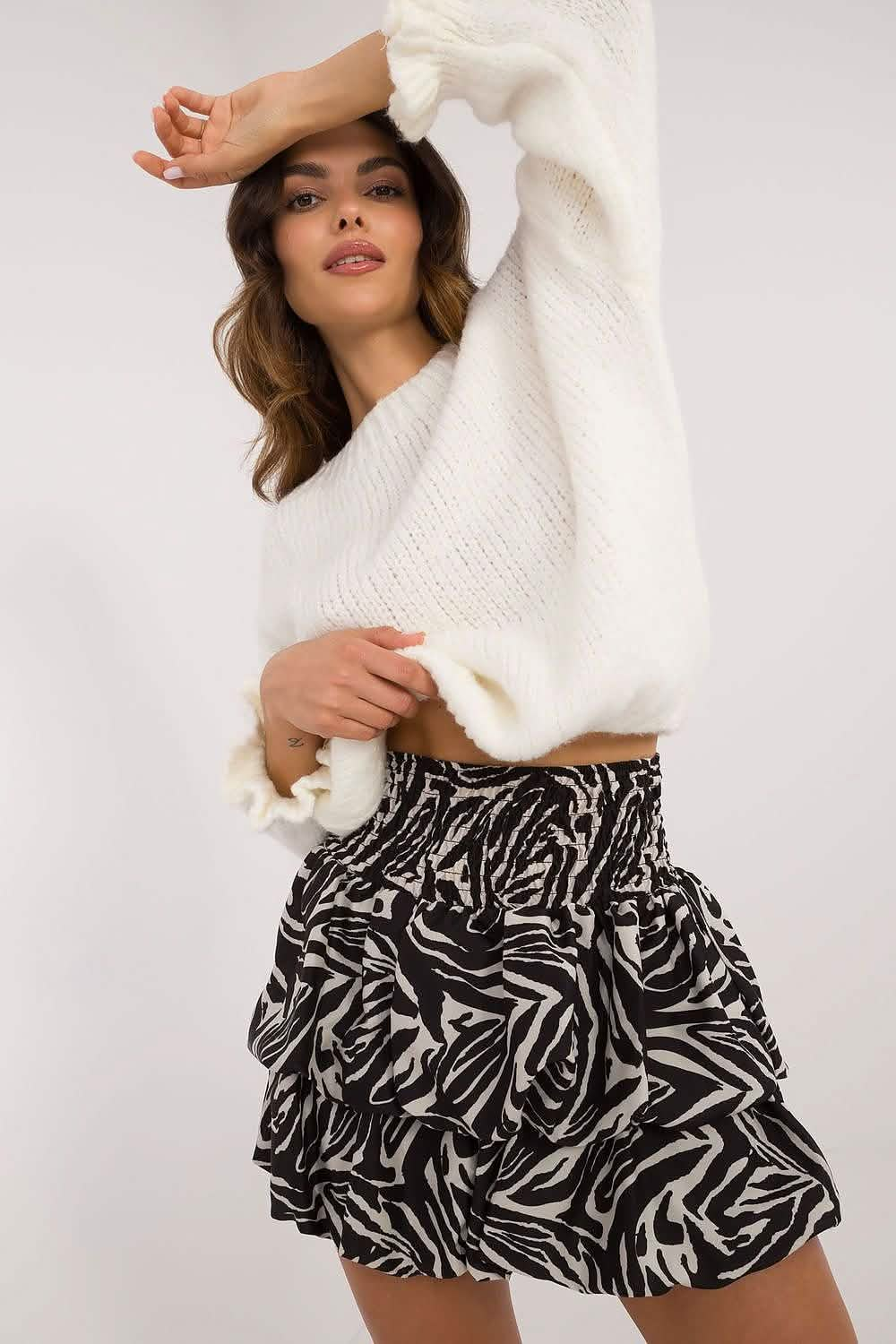 A black and white patterned ruffled mini skirt paired with a cream-colored sweater.