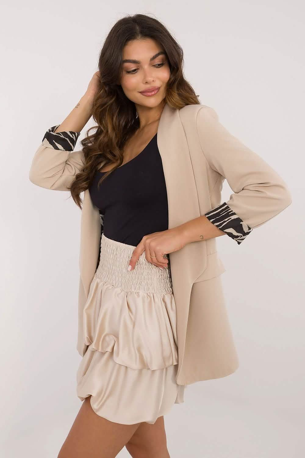 Beige blazer with striped cuff details worn with a ruffled mini skirt and black top.