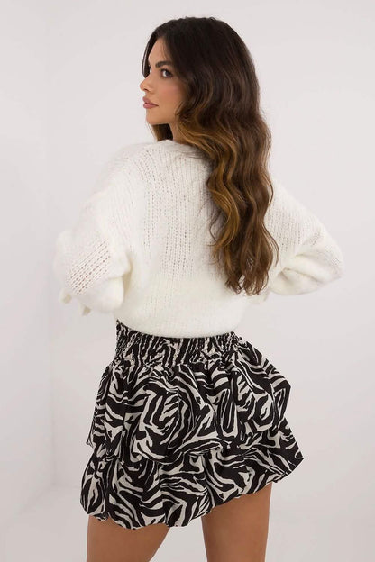 Black and white zebra-print ruffled mini skirt paired with a cream knit sweater.