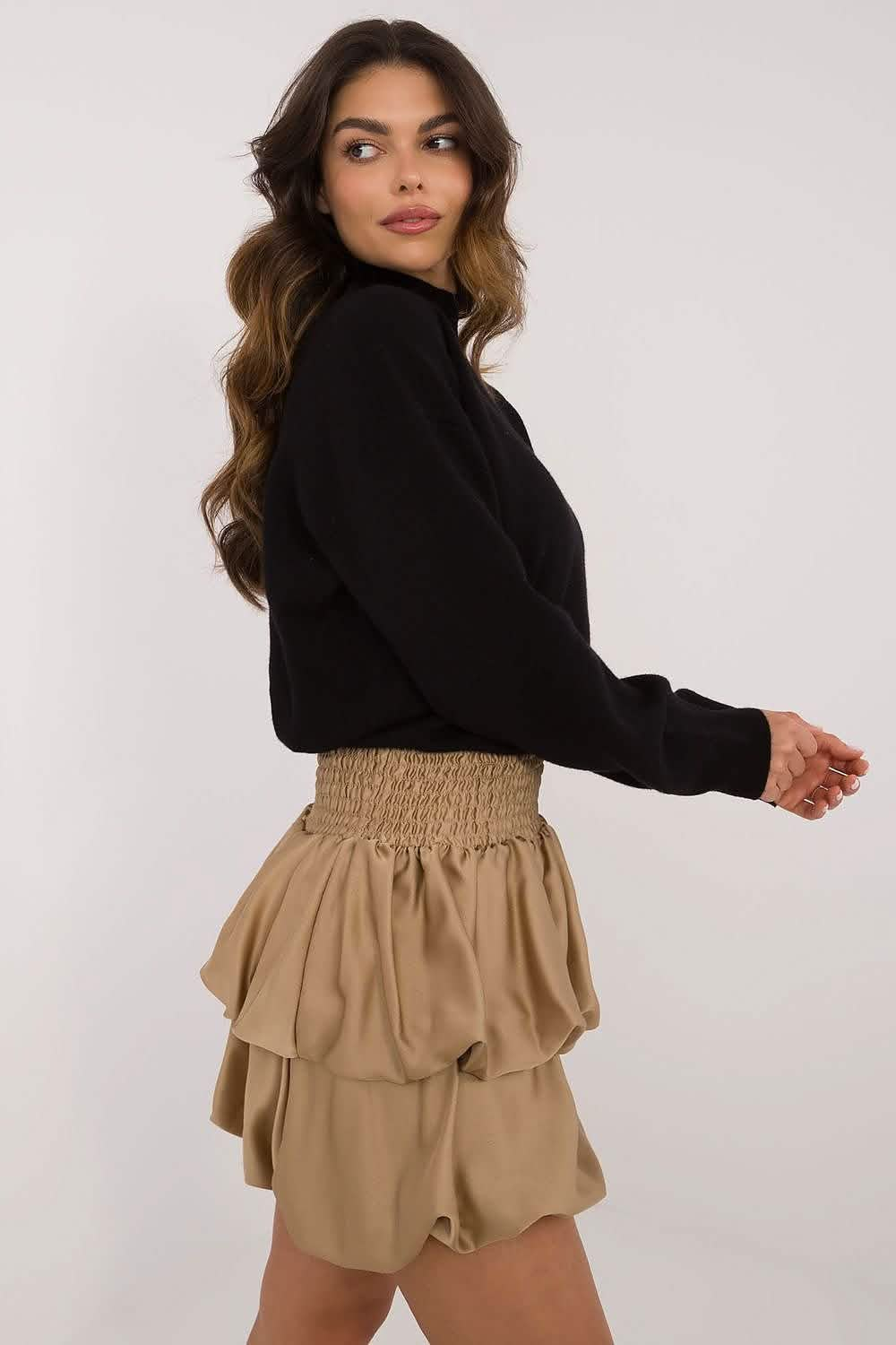 Ruffled beige mini skirt with an elastic waistband paired with a black turtleneck sweater.