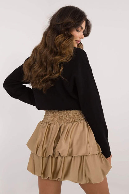 Beige ruffled mini skirt with an elastic waistband paired with a black sweater.