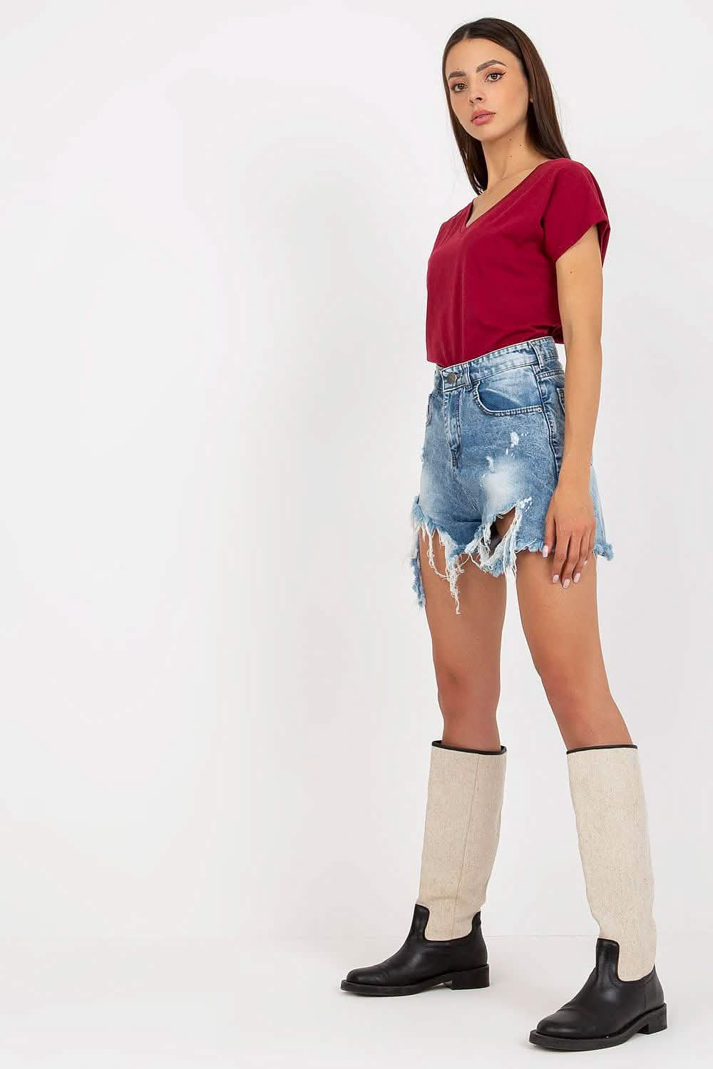 Distressed denim shorts with frayed edges paired with knee-high socks and boots.