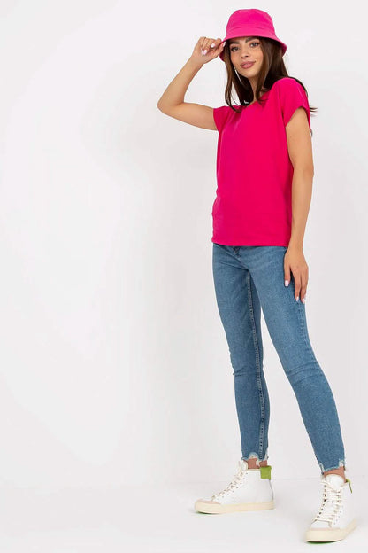 Person wearing a bright pink t-shirt, blue jeans, white sneakers and a matching pink hat.