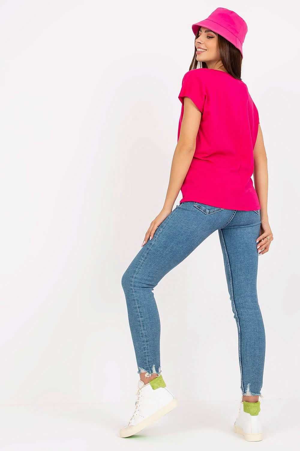 Person wearing a bright pink t-shirt, blue jeans, and white sneakers.