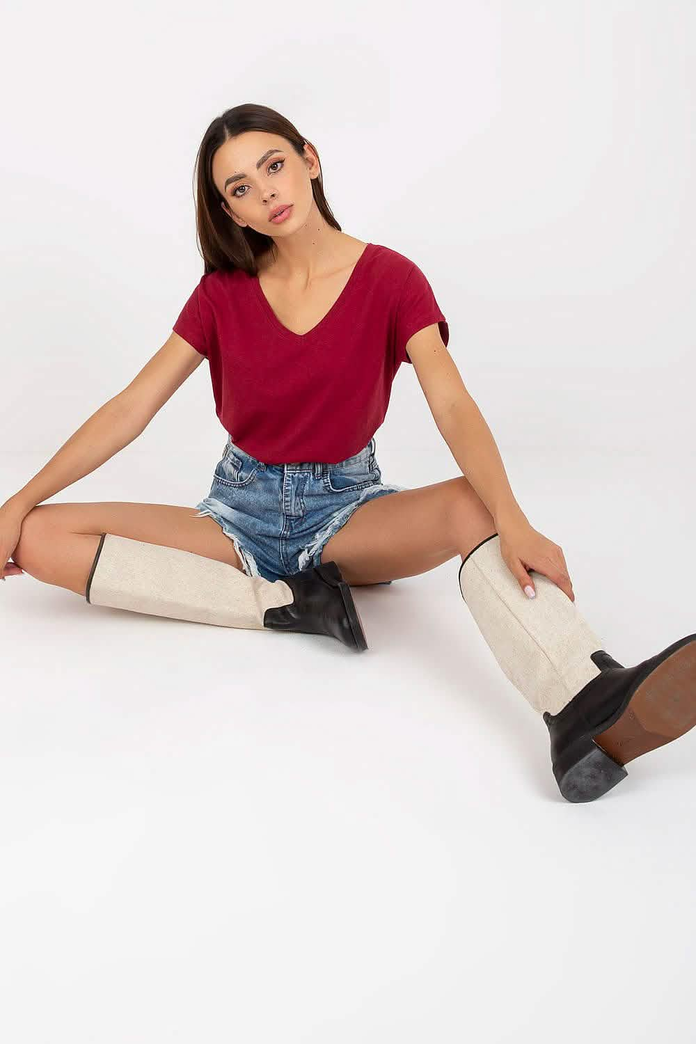 Red v-neck t-shirt paired with denim shorts and cream-colored boots.