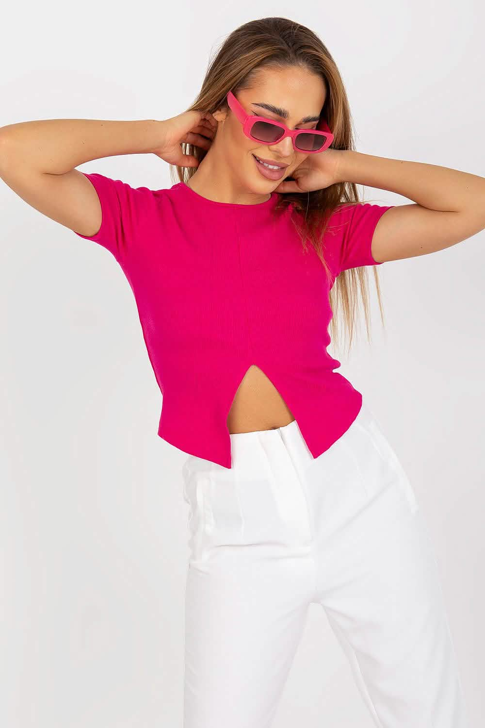 Hot pink cropped t-shirt with a side cutout paired with white pants.