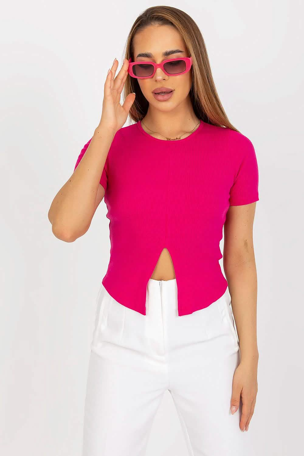 Hot pink cropped t-shirt with a center front slit worn with white pants.