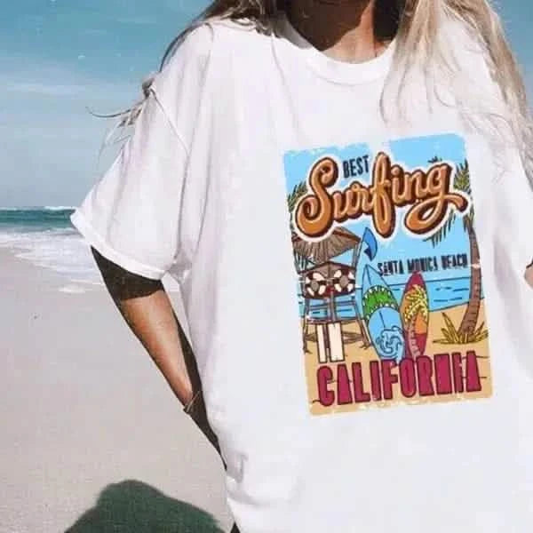 White t-shirt with a colorful California surfing graphic design featuring a lifeguard tower and palm trees.