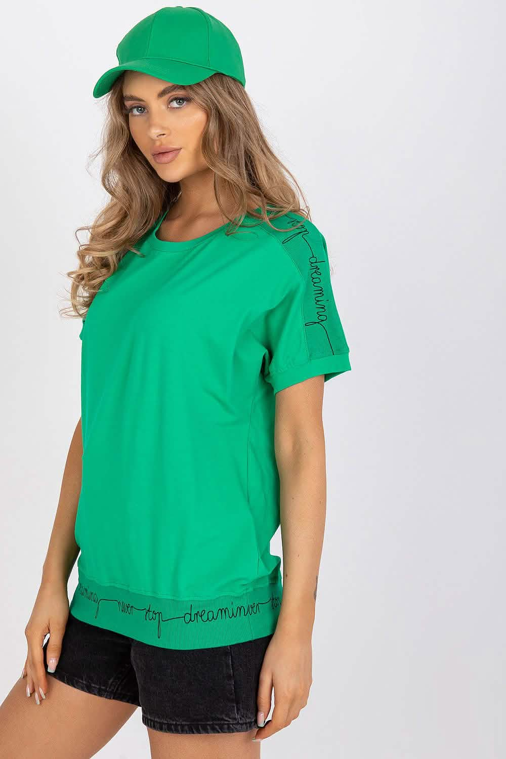 Bright green t-shirt with matching baseball cap worn with black denim shorts.