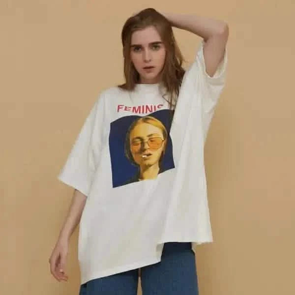 White t-shirt featuring ’FEMINIST’ text and a yellow-tinted graphic portrait wearing sunglasses.