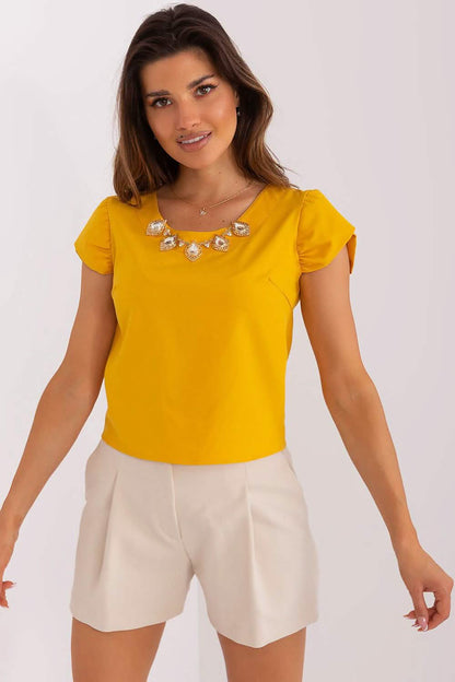 Bright yellow cap-sleeve top paired with white shorts and a crystal necklace.