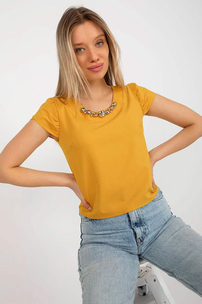 Mustard yellow short-sleeve top paired with light wash jeans.