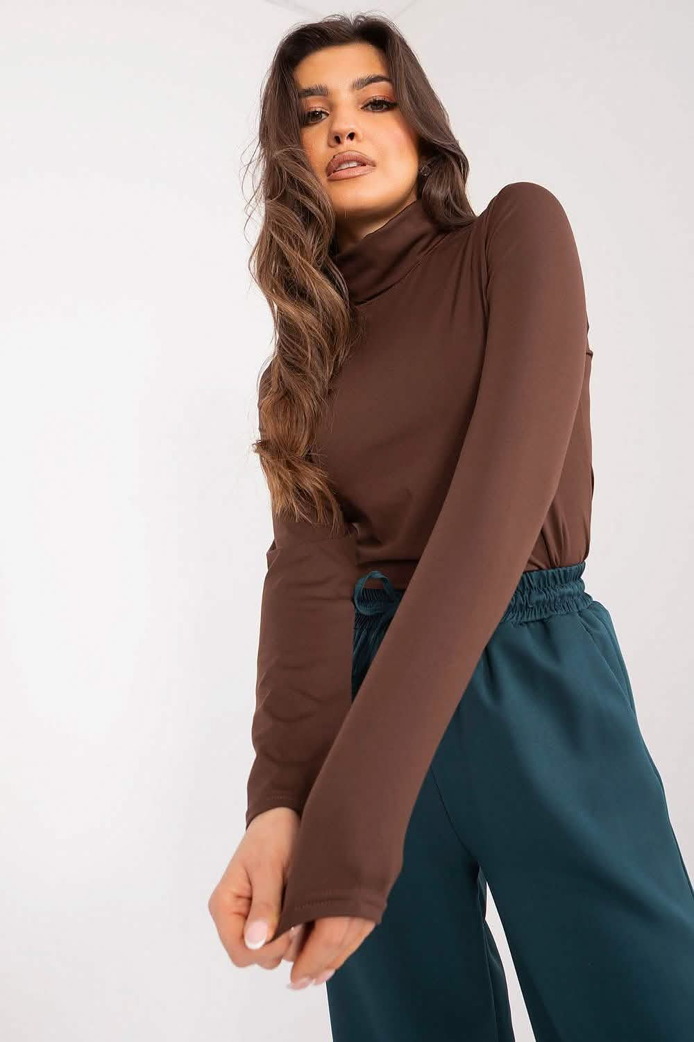 Brown turtleneck sweater paired with teal pants.