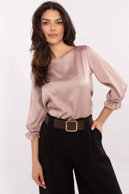 Dusty pink satin blouse with gathered sleeves paired with black trousers and a brown belt.