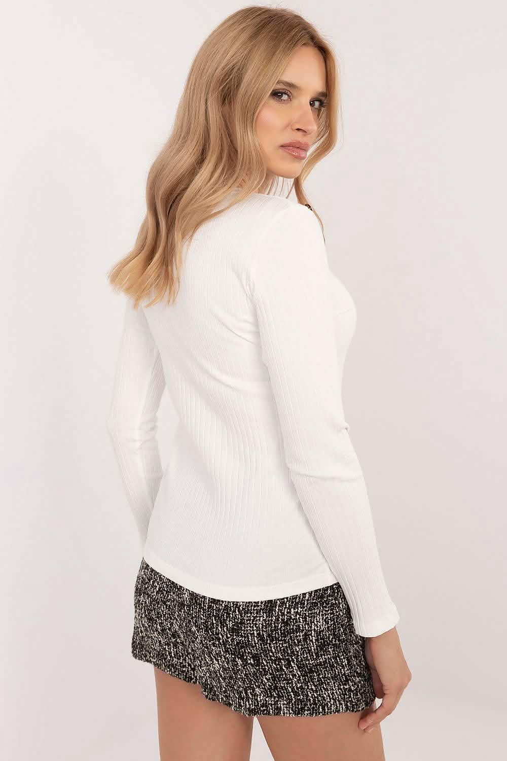 White long-sleeved sweater paired with a tweed mini skirt.