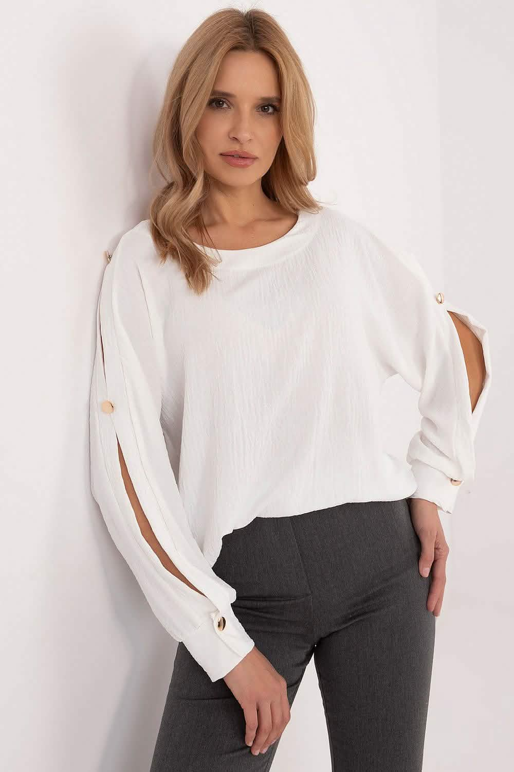 White blouse with split sleeves and button details paired with dark pants.