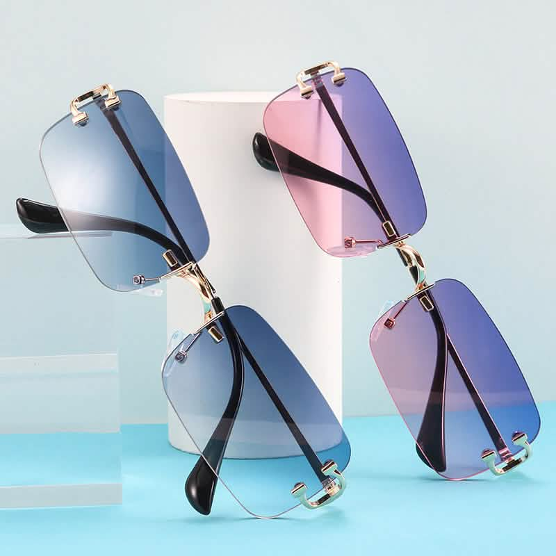 Small-frame sunglasses with gradient lenses in blue and pink hues, gold-tone trim, displayed against a modern minimalist backdrop.