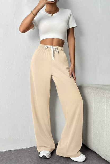 Beige wide-leg sweatpants paired with a white crop top and sneakers.