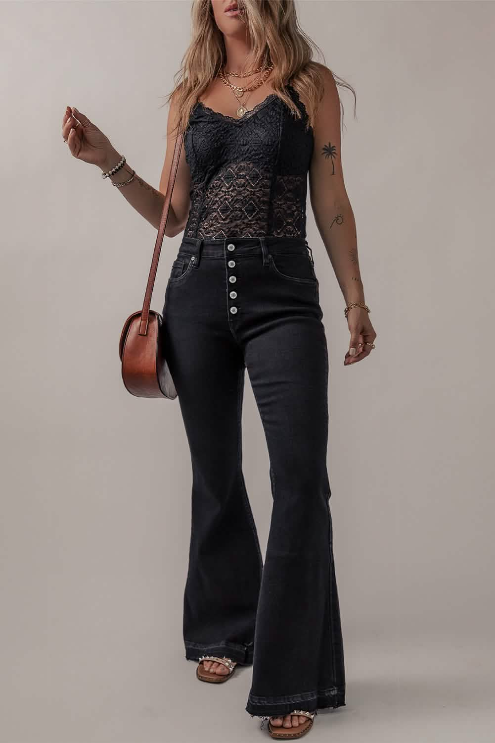 Black flared jeans paired with a lace camisole top and brown shoulder bag.