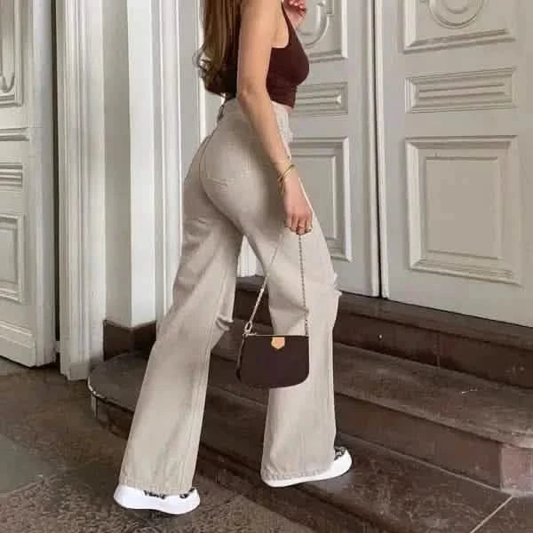 Wide-leg beige trousers paired with white sneakers and a brown handbag.