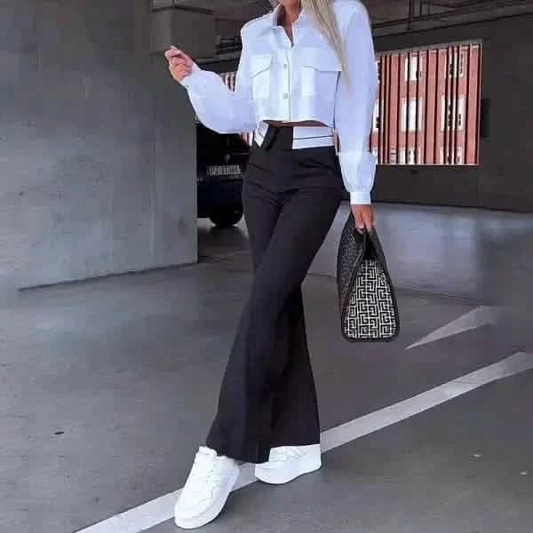 Stylish outfit featuring a cropped white button-up shirt paired with black flared pants and white sneakers.