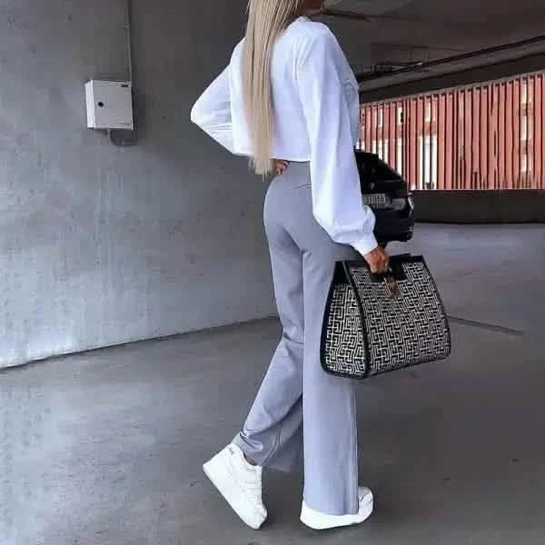 Stylish athleisure outfit featuring a white cropped sweatshirt, gray sweatpants, white sneakers, and a patterned handbag.