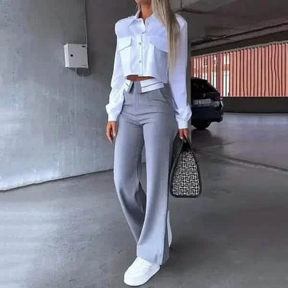 Stylish outfit featuring a cropped white button-down shirt paired with gray wide-leg trousers and white sneakers.