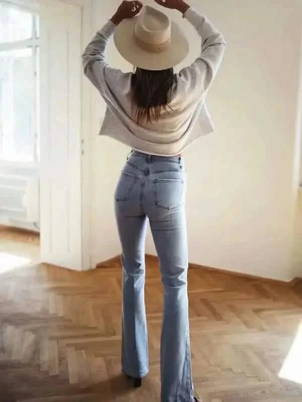 Flared blue jeans paired with a beige sweater and wide-brimmed hat.