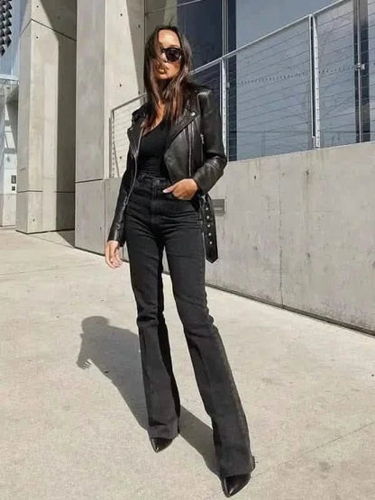 A black leather jacket paired with flared black jeans and sunglasses in an all-dark monochromatic outfit.