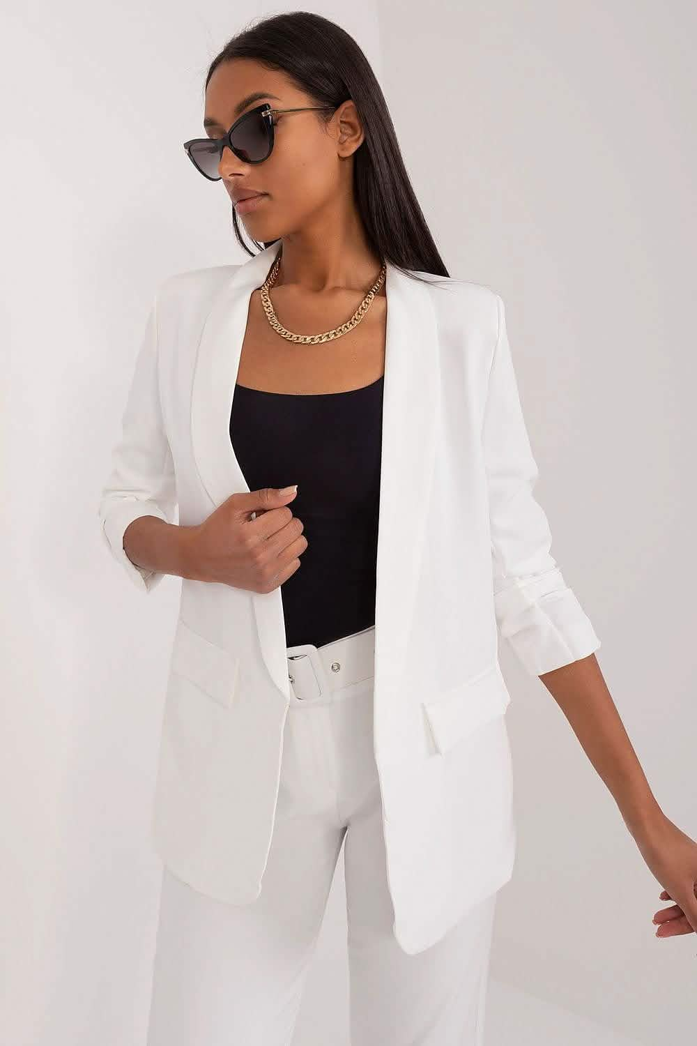 Crisp white blazer with three-quarter length sleeves worn over a black top.