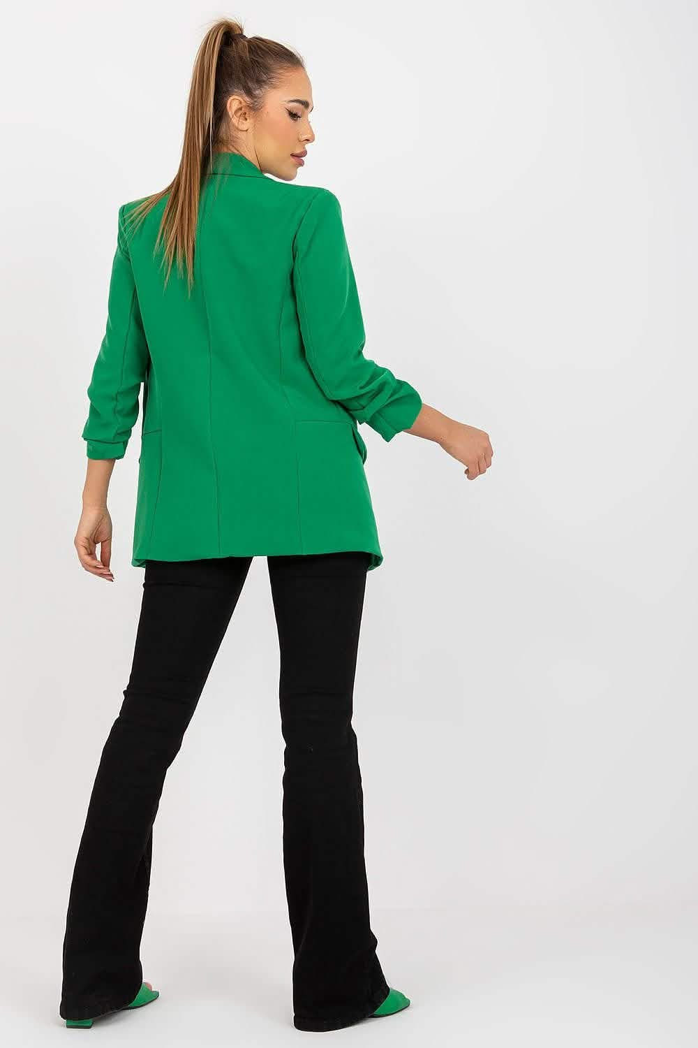 Bright green blazer with ruched sleeves worn with black flared pants.