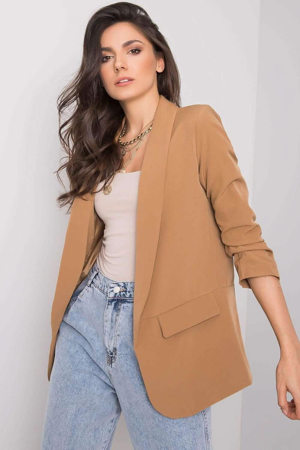 Tan blazer with rolled-up sleeves styled with light wash jeans and a white top.