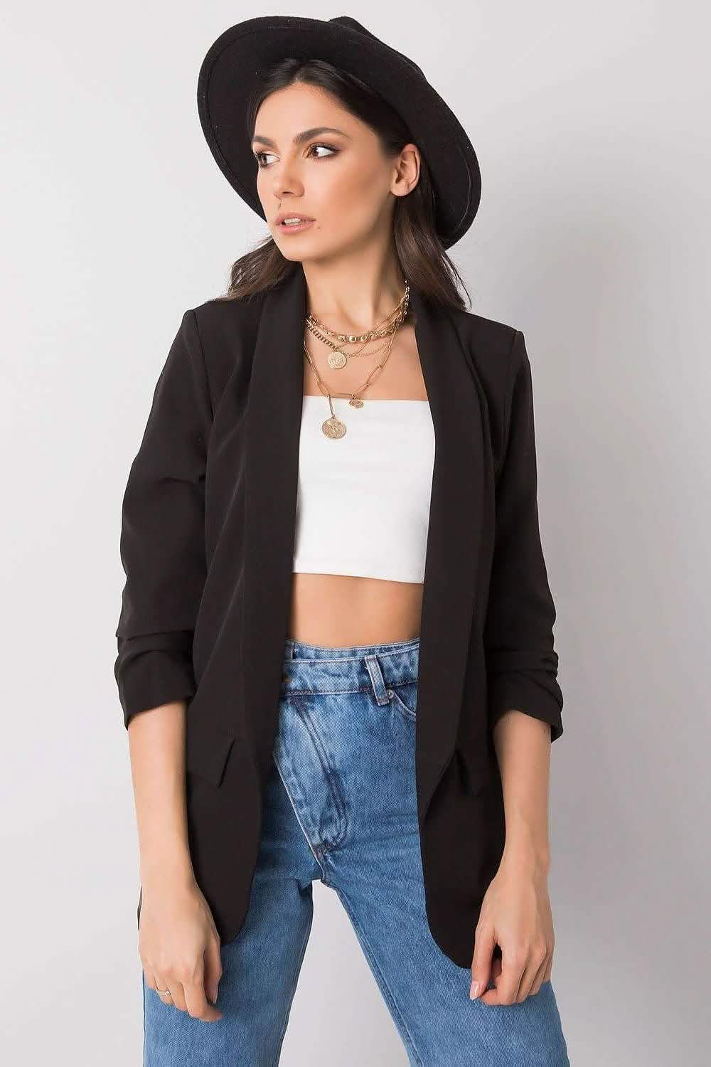 Black blazer with rolled-up sleeves styled over a white crop top and blue jeans.