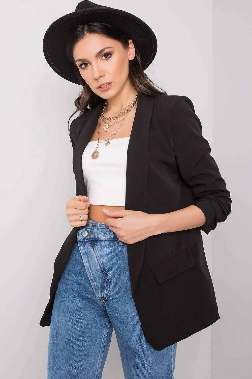 Black oversized blazer with ruched sleeves worn over a white top and blue jeans.