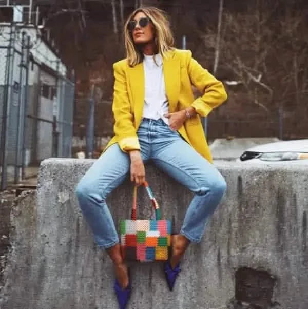 Bright yellow blazer paired with light-wash jeans and blue flats.