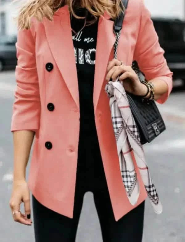 Coral pink double-breasted blazer worn with a black top and accessorized with a patterned scarf.